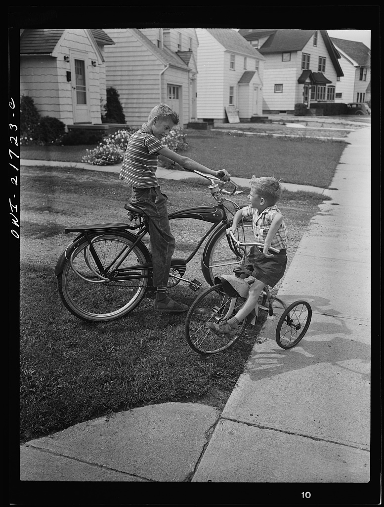 Howard and Earl Babcock playing in front of their house with their cycles [PHOTO: Library of Congress]