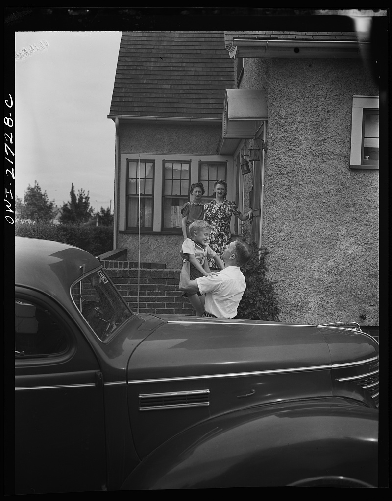 Mrs. Babcock, Shirley, and Earl greeting Mr. Babcock in front of the house [PHOTO: Library of Congress]