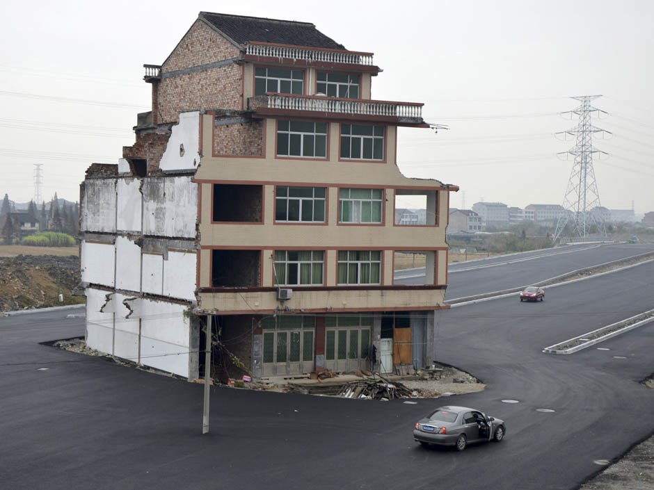 A car stops beside a house in the middle of a newly built road in Wenling, Zhejiang province, November 22, 2012. [PHOTO: REUTERS/China Daily]