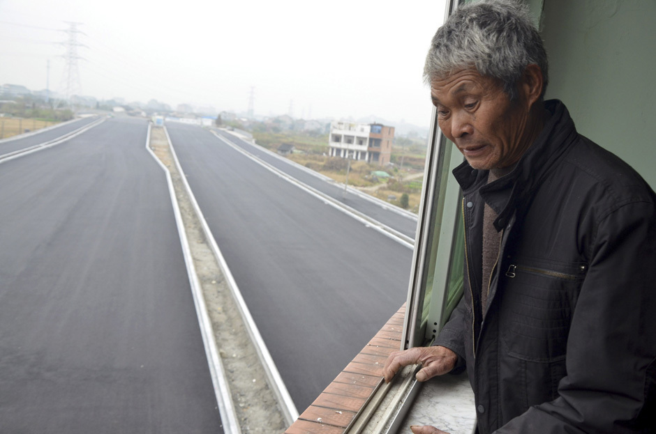 Mr. Luo looks down from his house which stands alone in the middle of a newly built road in Wenling, Zhejiang province, November 22, 2012. [PHOTO: REUTERS/China Daily]