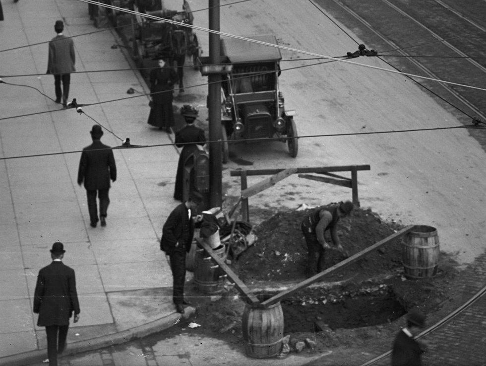 A close up view of a worker filling in a giant pothole on Main Street. Rochester, NY. c.1908. [PHOTO: Detroit Publishing Co. via Library of Congress]