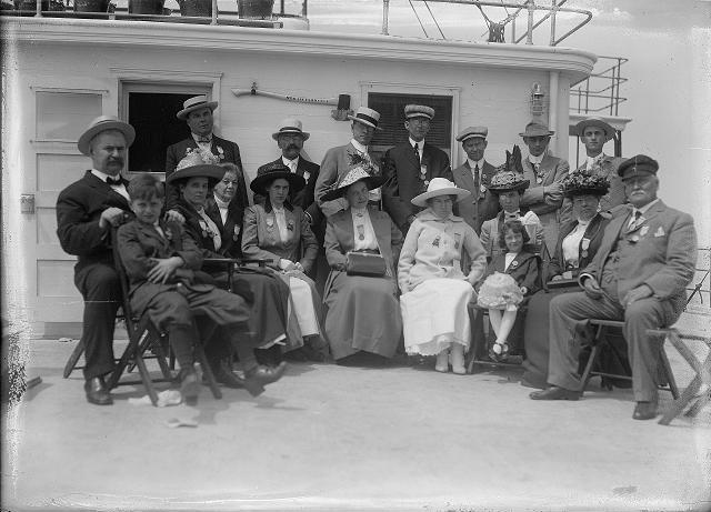 Crowd of people, including a band, in the bow of the car ferry Ontario I, as the boat leaves Charlotte. The group is the Rochester Common Council on an outing in Coburg. July 26, 1912. [PHOTO: Albert R. Stone]