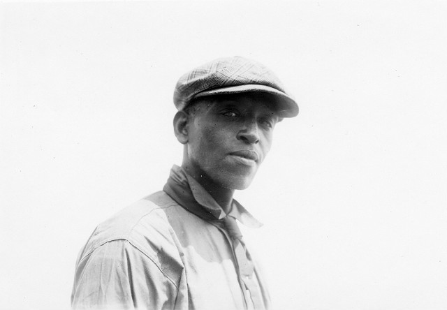 This is a close up of Robert Pernell, an African-American sand artist. He has been entertaining crowds at Charlotte Beach with his huge sand sculptures. Printed in Rochester Herald, August 6, 1922.