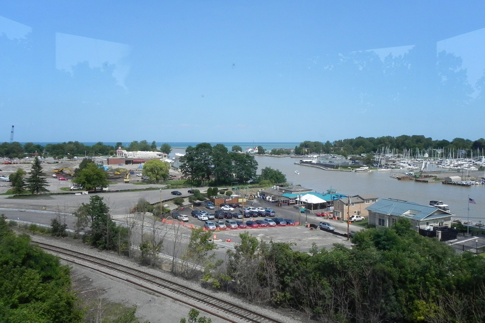 A view from atop the lighthouse, looking down on the area that was once marsh and sandbars. In the distance and slightly to the left, you can see Ontario Beach Park; the large white building in front of the line of trees is the Port of Rochester terminal. [PHOTO: Joanne Brokaw]