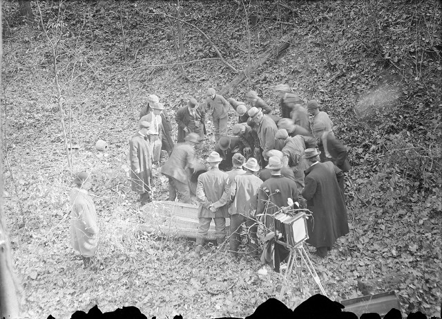 Detectives, men from the coroner's office, and bystanders gather around Francesco Manzello's dismembered body. [PHOTO: Albert R. Stone]