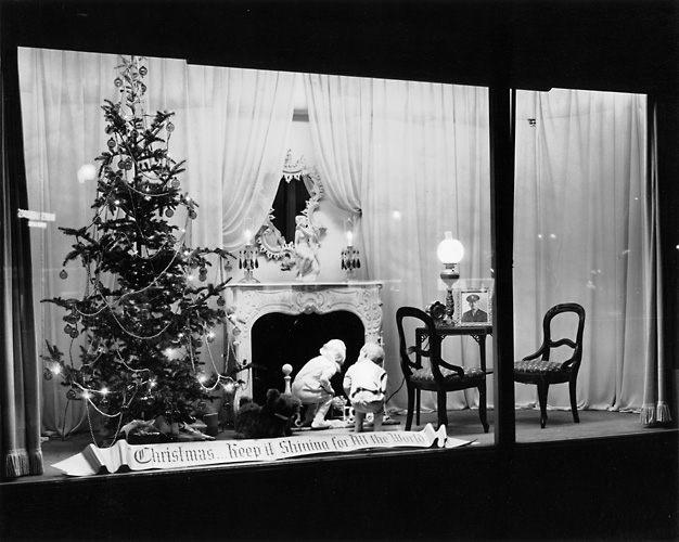 This view shows a tree and fireplace scene with children looking up the chimney. A banner proclaims 'Christmas: Keep it Shining For All the World.' c.1940. [PHOTO: Rochester Public Library]