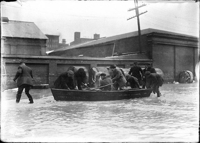 A group of men are pictured in and around a rowboat on Front Street, during the flood of 1913. March, 1913. [IMAGE: Albert R. Stone]