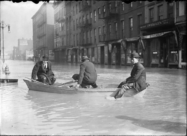 Three men ride a rowboat down flooded Front Street. They are passing J.G. Zweigle's. March, 1913. [IMAGE: Albert R. Stone]