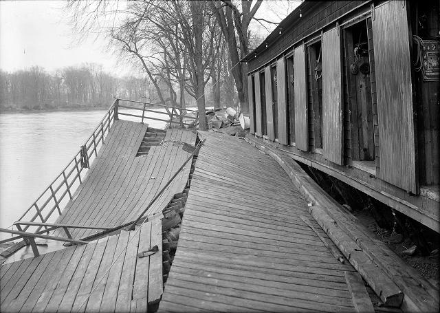 The Durand boathouse in Genesee Valley Park shows major flood damage. The Genesee River, again peaceful, flows past it. March, 1913. [IMAGE: Albert R. Stone]