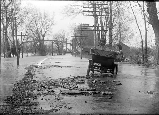 A man leans out of a car to observe the damage done on River Road by the 