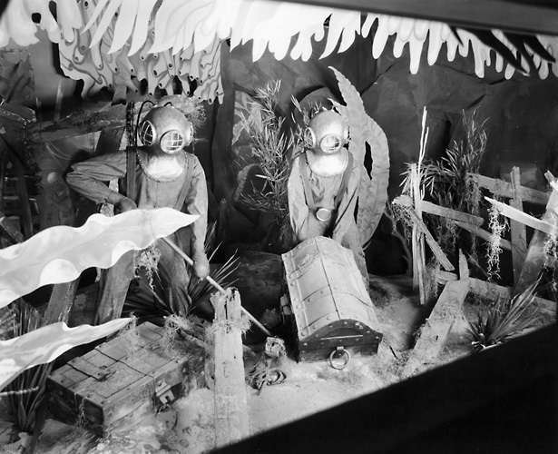 A Sibley's window display showing mannequins in scuba diver gear in an underwater scene with treasure chests. 1940. [PHOTO: Rochester Public Library]