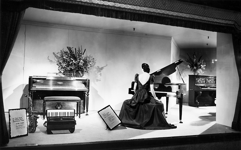 A Sibley's window display featuring a mannequin seated at a piano; also a second piano, a saxophone and an accordion. c.1940. [PHOTO: Rochester Public Library]