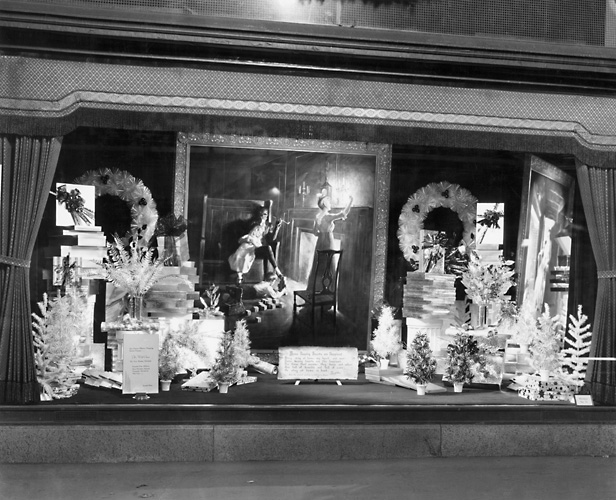 A Sibley's window display at Christmas time showing a variety of wreaths and artificial trees. Also features a copy of an oil painting by William L. Taylor based on a poem by Henry Wadsworth Longfellow, 'Home Keeping Hearts are Happiest.' 1940. [PHOTO: Rochester Public Library]