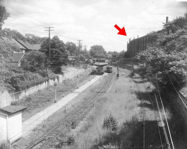 A view of the Rochester Subway looking east from the Meigs Street bridge. A westbound car is shown approaching the Goodman-Meigs station. The Sherwood Shoe Company building on Goodman Street and Uhlen Place is seen in the right background.  [PHOTO: Rochester Municipal Archives]