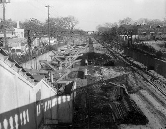 A view looking east along the Rochester Subway bed from the Monroe Avenue bridge, showing the stairway leading from the bridge to the Monroe Avenue subway station. The station has been partially dismantled, in preparation for the construction of Interstate 490 in the subway bed. [Image from Rochester Municipal Archives]