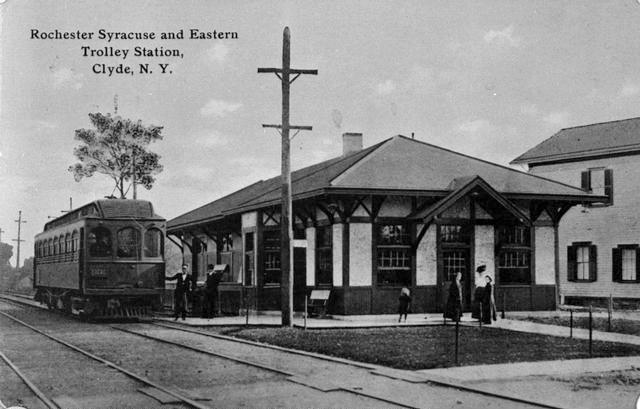 A view of the Rochester, Syracuse and Eastern interurban trolley station in Clyde NY. A street car, tracks and people are seen. This station was built between 1906 and 1911, and was a stopping point between Rochester and Syracuse.